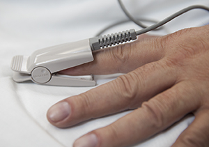 Patient's hand with pulse oximeter on finger.