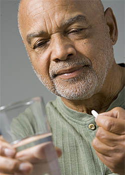Senior man about to take a pill with a glass of water.
