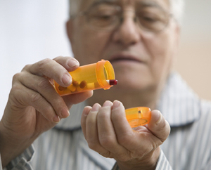 Senior man shaking out pills into his hand.