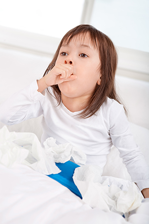 Sick little girl coughing in bed.