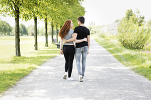 Teenage boy and girl walking in park.