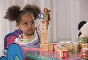 Toddler girl playing with play blocks.