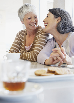 Two women friends talking, having coffee and dessert.