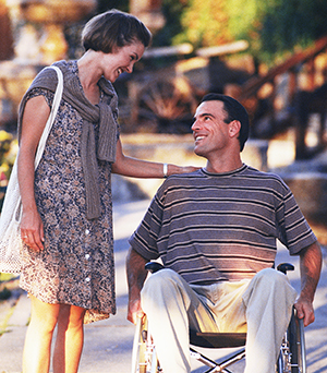 Woman and man in wheelchair taking walk outdoors and talking.
