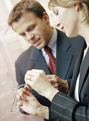 Woman and man looking at glasses at optician's.