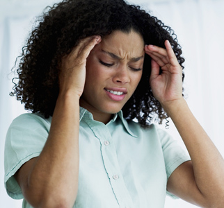 Woman frowning, with hands to forehead