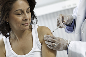 Woman getting vaccine shot by health care provider.