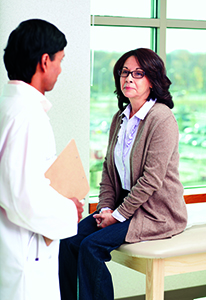 Woman sitting on exam table on provider's office. Provider is talking to her.