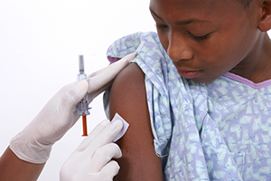Healthcare provider giving boy injection in upper arm.