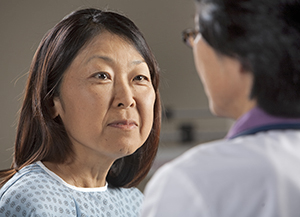 Woman wearing hospital gown listening to healthcare provider