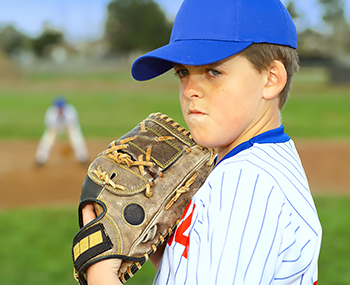 Young boy in softball uniform holding softball glove