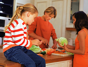 Young family making salad in kitchen.