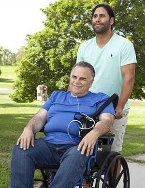 Man with nasal cannula in wheelchair. Another man pushing wheelchair.