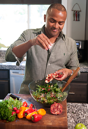 Man making salad in kitchen.