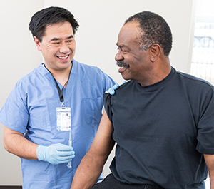 Healthcare provider preparing to give man injection in upper arm.