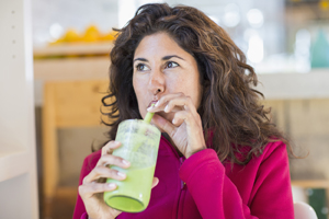 Woman drinking a fruit smoothie from a straw.