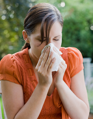 Woman holding tissue to nose.