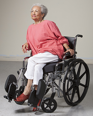 Woman in wheelchair leaning to side to take pressure off one leg.