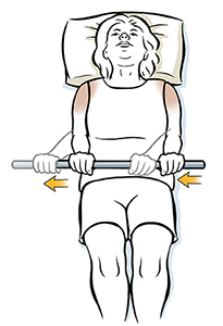 Woman lying on back holding wand doing external rotation shoulder exercise.