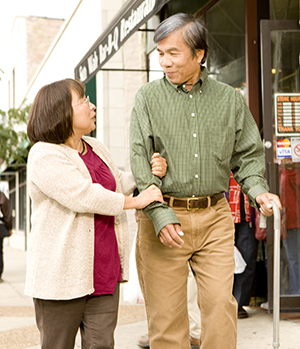 Woman walking with man with cane.