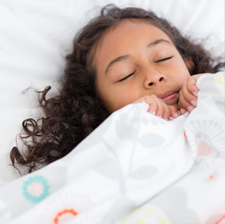 Niña durmiendo con sábanas alrededor de su cara como si estuviera asustada.